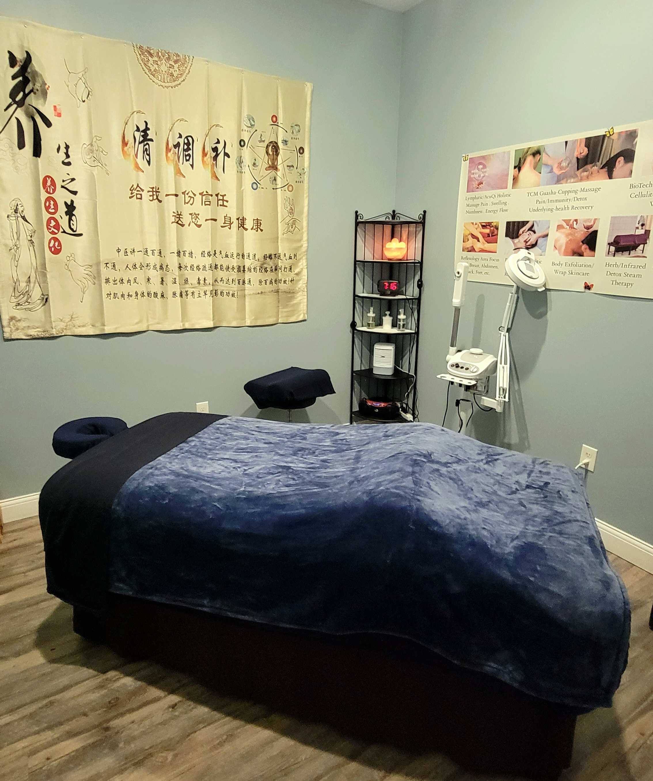 A private treatment room at Holistique Healing Spa with a massage table and TCM wall art.